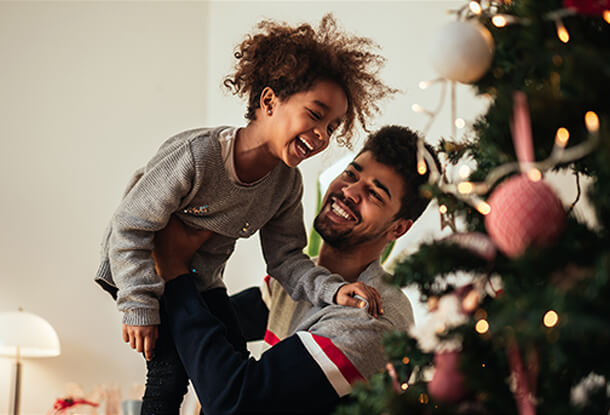 Father holding child near Christmas tree